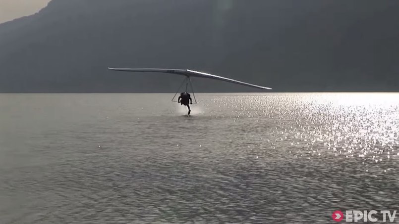 person hang gliding and touching the water