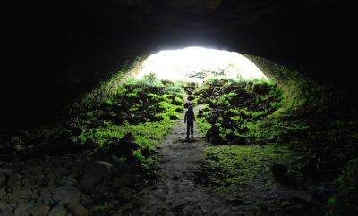 person standing in cave mouth