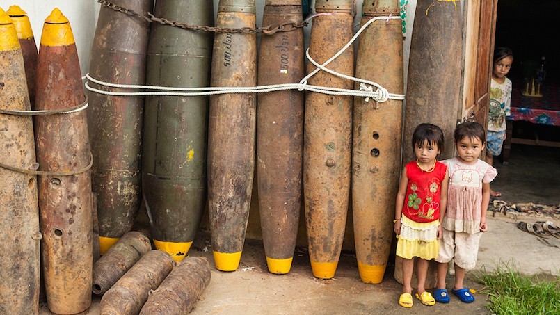 young girls standing by old bombs