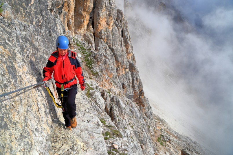 Climber woman on traverse section of via ferrata Dolomite Alps