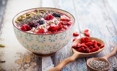 Breakfast berry smoothie bowl topped with goji berries,raspberry, blackberry, pumpkin, sunflower and chia seeds. soft focus