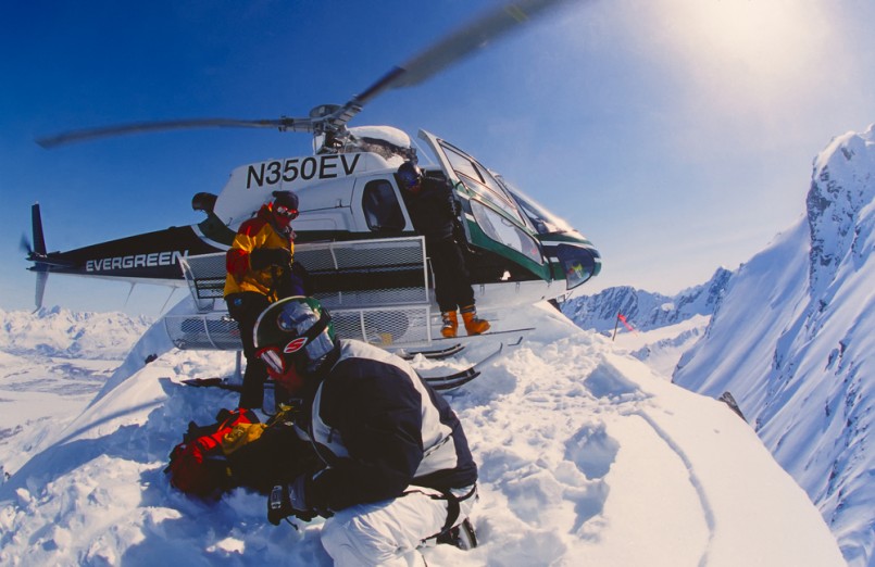 Snowboarder Esben Pedersen being dropped of by helicopter onf an isolated peak in the Chugach Mountains