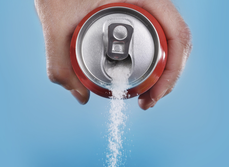 hand-holding-soda-can-pouring-a-crazy-amount-of-sugar-in-metaphor-of-sugar-content-of-a-refresh-drink-isolated-on-blue-background-in-healthy-nutrition-diet-and-sweet-addiction-concept