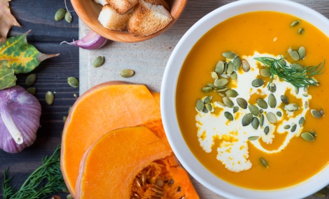 Pumpkin soup among autumn leaves on a wooden table