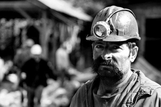black and white photo of coal miner with mustach and mining helmet on
